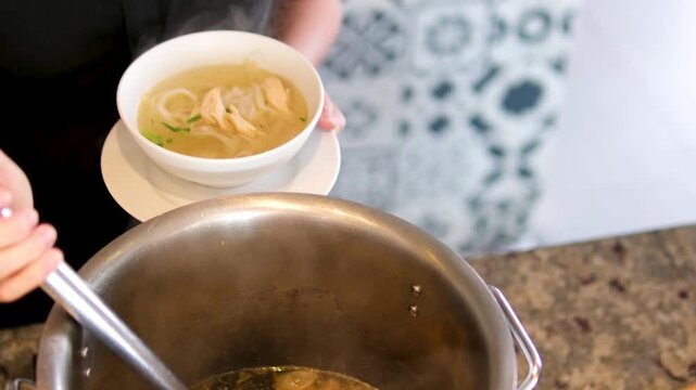 Soup cooking pot pho bo hot pot cook fa pho soup vietnam close-up deep frying pan in broth is cooked pork bones girl stirs her food in a restaurant buffet selection of ingredients in cooking Vietnam