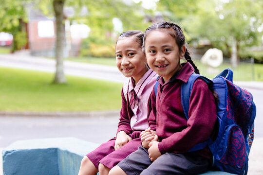 Samoan children in school uniform sitting on the blue concrete ledge