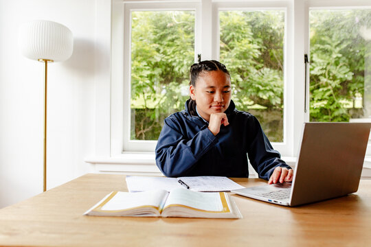 Teenage Samoan girl doing her homework on the table using laptop