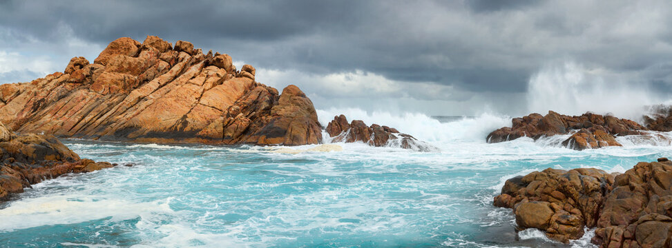 Panorama view of large waves crashing through channels along a rocky coastline