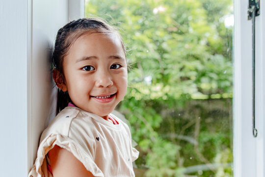 Young Samoan girl sitting on windowsill leaning against the jamb