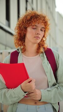 Determined young student grasping a red folder, embodying focus and ambition for upcoming academic challenges. A moment of concentration as they prepare to tackle their educational journey ahead.