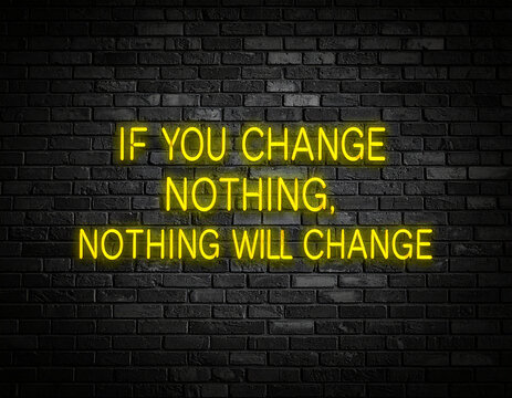 Leuchtende gelbe Neonschrift "if you change nothing, nothing will change " auf dunkler Backsteinmauer