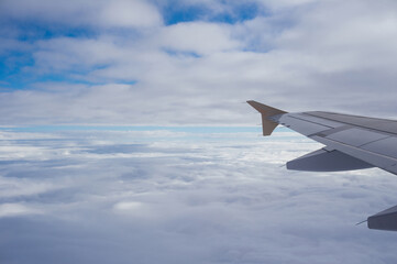 Fototapeta premium View of an airplane wing over a thick blanket of clouds