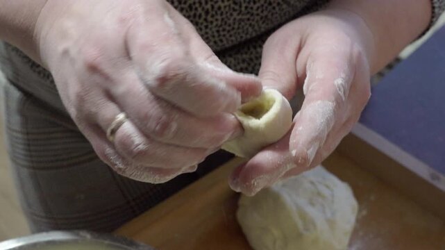 process of sculpting dumplings in female hands, Close-up of hands forming a small piece of raw dough