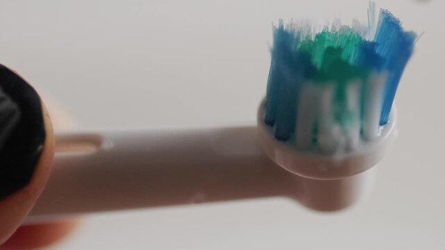 Applying toothpaste to electric toothbrush head close up