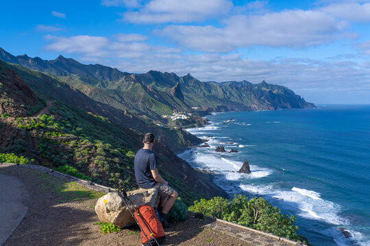 A tourist during a break in Anaga Rural Park, with Almaciga village in the distance. Canary Islands. Tenerife.