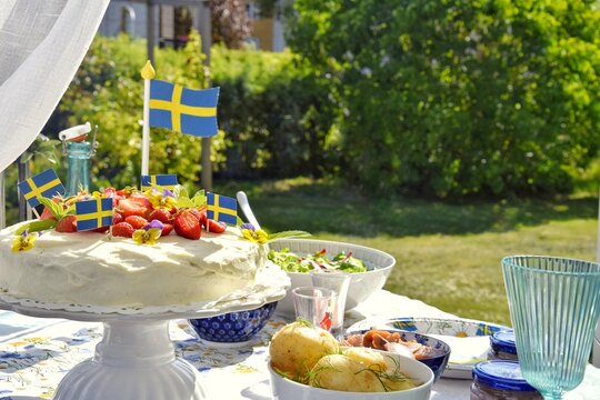 A cake decorated with strawberries, new potatoes and herring to celebrate the summer solstice on the festive table.Midsummer in Sweden.