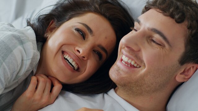 Close up happy Caucasian couple boyfriend girlfriend talking on bed home bedroom faces woman man chatting gossip laughing smiling cuddle female male love relationship bonding joyful romance together