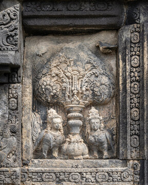 Closeup vertical view of ancient stone bas-relief of kalpataru tree and kinnara on base of Shiva temple, Prambanan, Yogyakarta, Central Java, Indonesia