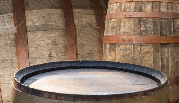 Wooden barrels in rustic cellar, warm amber light highlights oak staves and patina, barrels set for wine and whisky aging, subtle