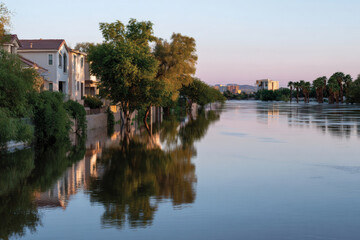 Obraz premium An evening view of houses partially submerged amid calm waters, highlighted by soft light that creates a peaceful, reflective atmosphere.