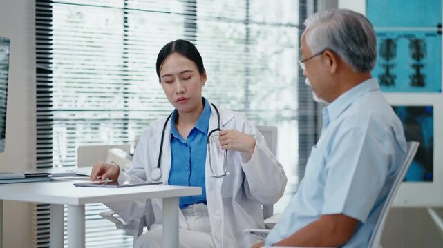 Asian senior man having health consultation and check up and  with female doctor at clinic.woman doctor examine elderly Asian man patient use stethoscope listening to the sounds of heart and lungs.
