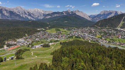 aerial, bird view, Seefeld, Austria. View on Seefeld in Tirol village, in the valley between impressive alpine mountains. View from grassy hill on the town, pine tree at the side. Beautiful tourist mu