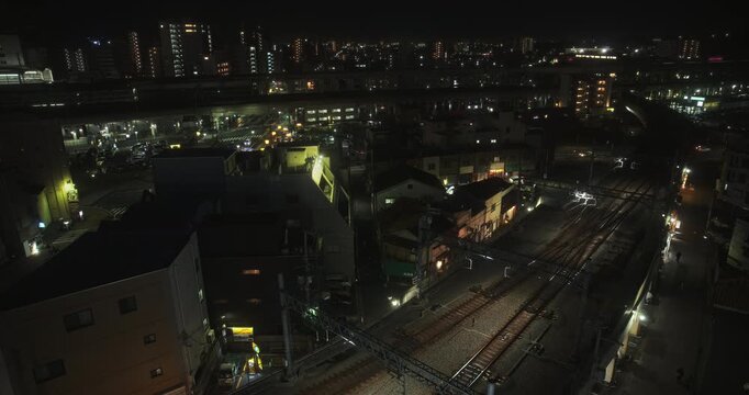 Lights on empty tracks and view of silhouetted Japanese city at night - high shot