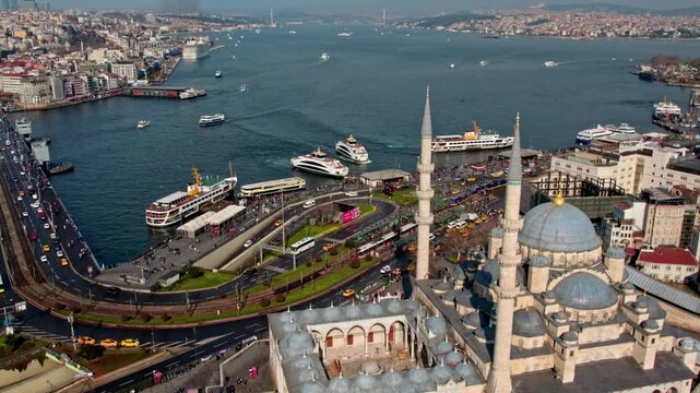 The New Mosque (Emin&ouml;n&uuml;) in the foreground with the Galata Bridge and the Bosphorus behind it. Ferry traffic, waterfront road, and dense urban fabric define the Istanbul panorama.