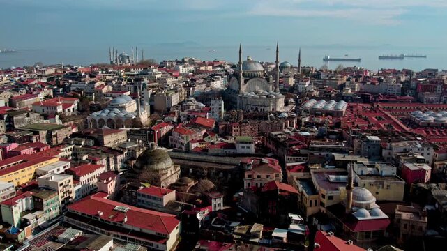 Aerial panorama of Istanbul&rsquo;s Emin&ouml;n&uuml; district featuring the New Mosque, surrounded by dense urban fabric and Grand Bazaar rooftops, with the Sea of Marmara and ships in the background.