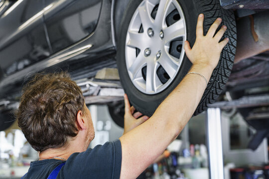 car on a car lift in auto repair service station. A mechanic is changing tires.