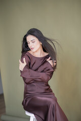 Fototapeta premium A beautiful girl in a chocolate dress smiles and poses with fresh flowers
