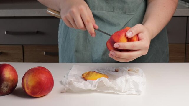Woman cutting bruised parts from overripe peach for zero waste cooking