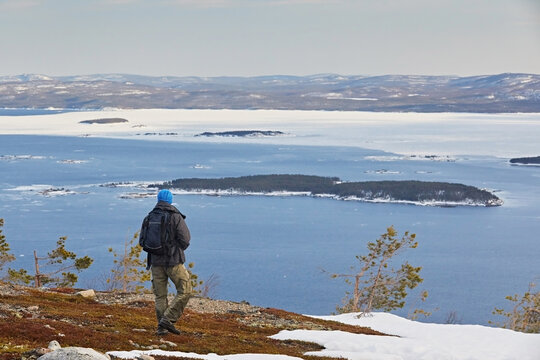 A tourist walks through the tundra overlooking a sea of ​​ice floes.
