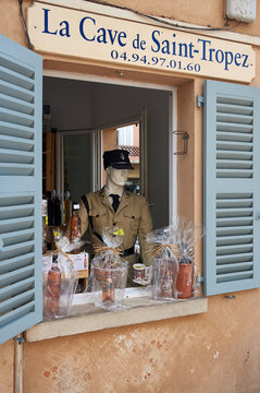A shop window display at La Cave de Saint-Tropez featuring a mannequin in a gendarme uniform and bottles of rose wine, Saint-Tropez, Provence-Alpes-Cote d'Azur, France.