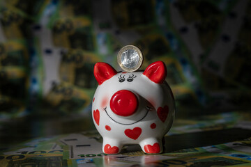 Obraz premium A piggy bank against a background of 100 euro bills in a light and shadow pattern