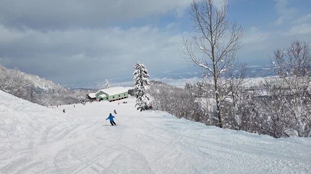 Furano, Japan: Slow motion point of view footage of a snowboarder riding the slope full of fresh snow of the Furano ski resort on a sunny winter day