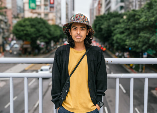 Young man wearing bucket hat standing on urban bridge