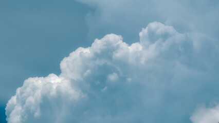 Fototapeta premium Close-up of a voluminous, fluffy white cumulus cloud against a serene blue sky, highlighting its intricate textures and the peaceful vastness of nature's beauty