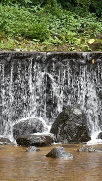 Artificial waterfall, decorated with large rocks below, creates a natural and serene feel. Ideal for promoting vertical tourism and visual relaxation.