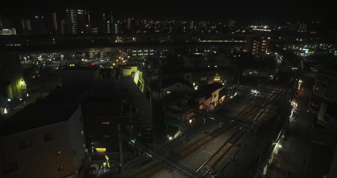 Cinematic view of Japanese city at night with passing glowing trains - high shot
