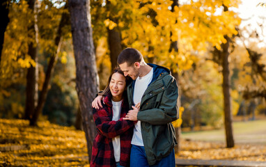 Fototapeta premium Smiling multiracial couple in love walking in an sunny autumn park.