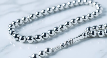 Obraz premium Close-up of a Silver Prayer Beads Rosary on a Marble Surface.