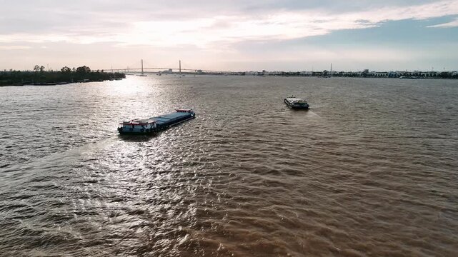Aerial view of cargo barges sailing on the mekong river in vietnam at sunset