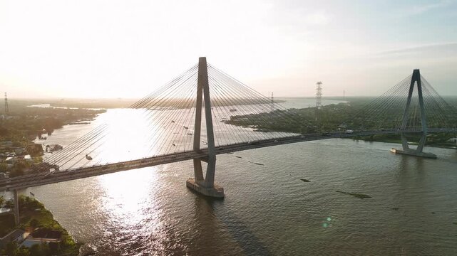 Aerial view of can tho bridge crossing mekong river with sunset sun flare and traffic