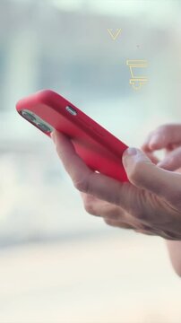 Person holding red smartphone, scrolling through shopping app with neon abstract shopping cart icon overlay, adding items for fast online purchase and e-commerce experience