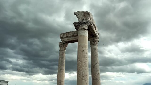 Video of ancient columns standing tall at Laodikeia ancient city, set against a dramatic cloudy sky background.