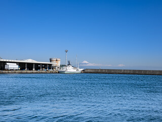静岡県御前崎港に停泊する漁船と駿河湾越しに望む冠雪した冬の富士山
