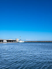 静岡県御前崎港に停泊する漁船と駿河湾越しに望む冠雪した冬の富士山
