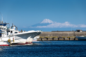 静岡県御前崎港に停泊する漁船と駿河湾越しに望む冠雪した冬の富士山
