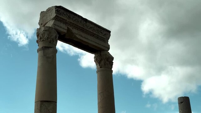 Video of ancient columns standing tall at Laodikeia ancient city, set against a dramatic cloudy sky background.