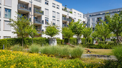 Obraz premium Flowers and Greenery Surround Buildings in a Residential Area on a Sunny Day