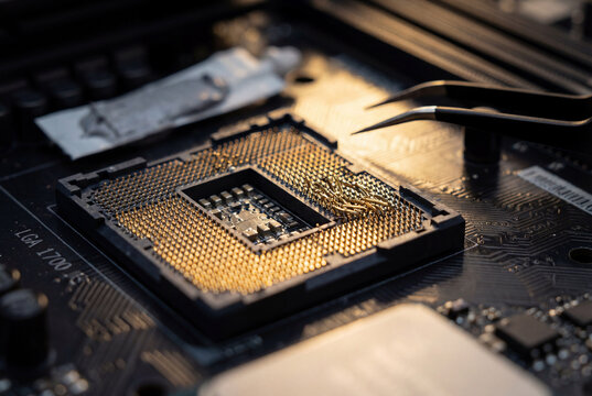 Macro view of repairing bent pins on computer motherboard CPU socket using tweezers
