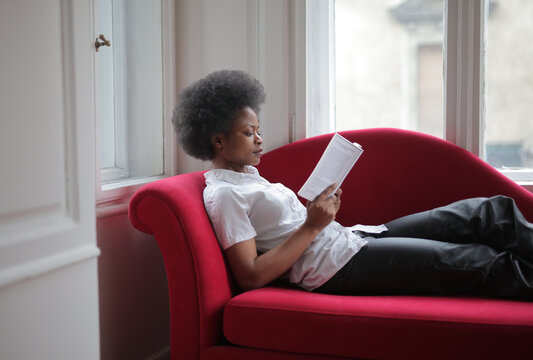 woman reading a book sitting on the sofa