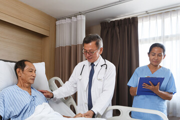 Obraz premium senior asia doctor visiting male cancer patient in hospital bed while female nurse holding clipboard taking notes. Professional medical team providing healthcare and treatment in elderly care home.