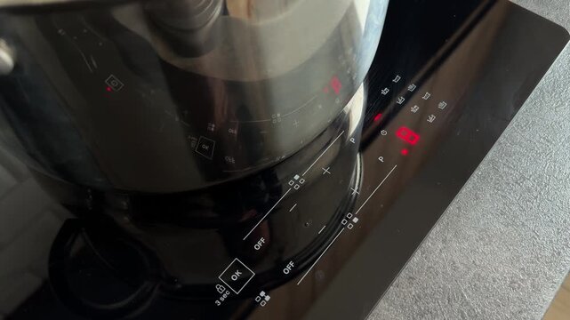 Set the induction hob power to level 8 for fast boiling. Close-up of a manual control touch sensor on a modern electric stove. High-performance control of kitchen appliances.