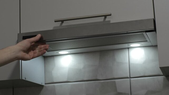 Man taking off a stove extractor hood to turn off ventilation and lights on kitchen. Close up