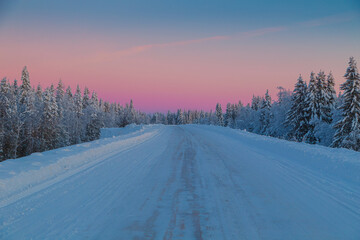 Obraz premium Road in the winter forest at sunset. Amazing winter landscape.