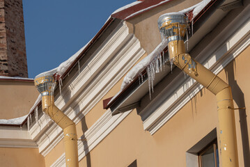 Naklejka premium Icicles of ice hang from the roof.The danger of ice falling from the roof onto your head.Snow removal in winter.